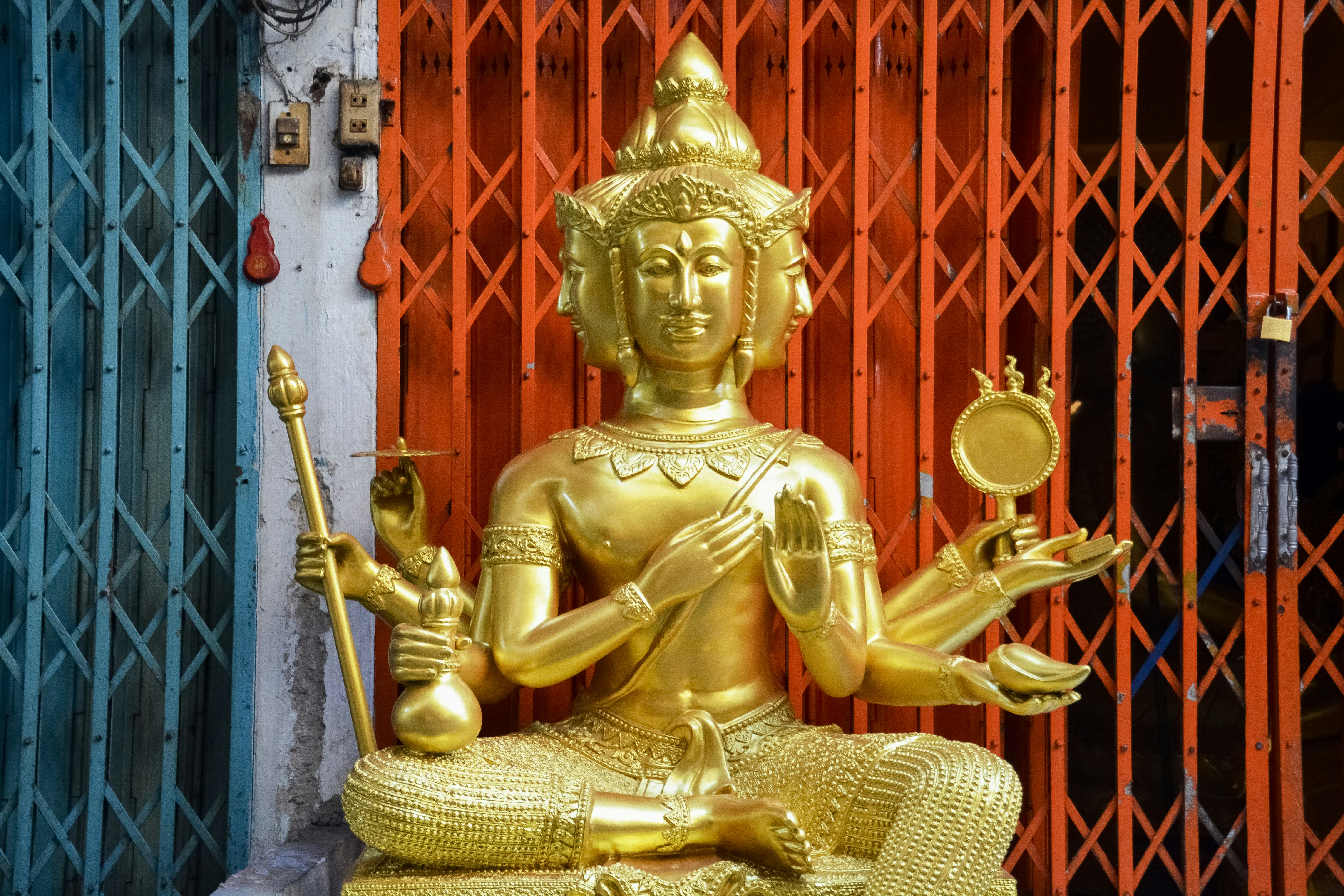 gold buddha statue near red wooden door